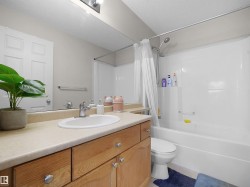 Bathroom featuring a light-toned vanity countertop, white sink basin, and wood-finish cabinetry with silver-tone hardware - 