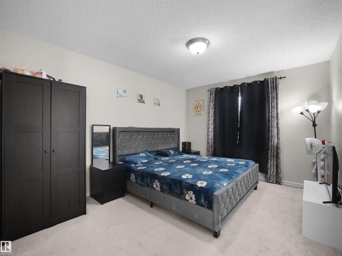 Spacious room featuring neutral carpeting, a window with dark drapery, and a flush-mount ceiling light fixture - 8111 7 Avenue Sw, Edmonton, AB - Indoor Photo Showing Bedroom