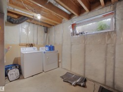 Unfinished basement featuring exposed wood joists and a utility sink - 