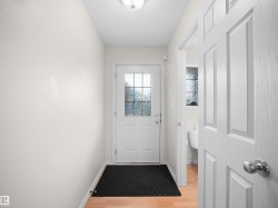 Entryway featuring a white door with divided light glass, light wood-finish flooring, and a flush mount ceiling light - 