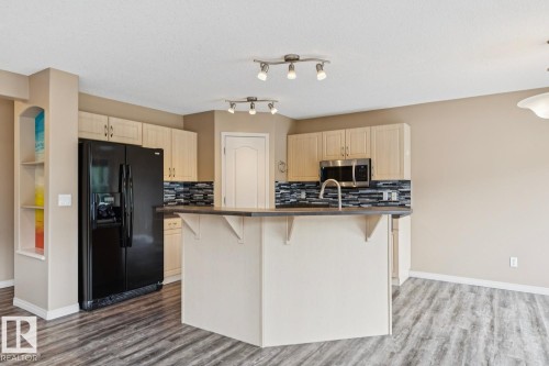 Modern kitchen featuring light wood-finish cabinetry, a black appliance suite, and a textured tile backsplash - 16765 119 Street Nw, Edmonton, AB - Indoor Photo Showing Kitchen