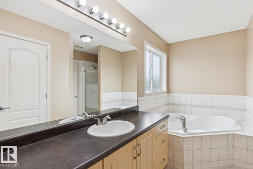 Bathroom featuring a vanity with a single basin sink, laminate countertop, and wood-finish cabinetry - 16765 119 Street Nw, Edmonton, AB - Indoor Photo Showing Bathroom