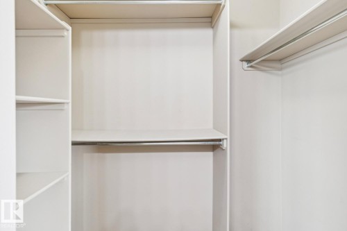 Built-in closet system featuring white shelving and chrome hanging rods - 16765 119 Street Nw, Edmonton, AB - Indoor Photo Showing Other Room