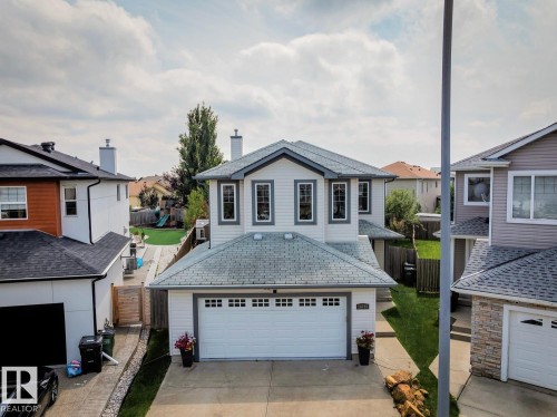 Two-story residence featuring white siding with contrasting trim, a front-facing attached garage, and a peaked roofline - 16765 119 Street Nw, Edmonton, AB - Outdoor