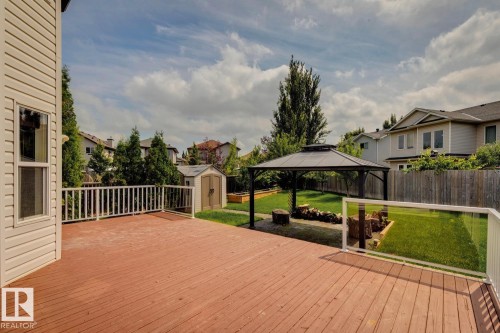 Spacious red-stained wood deck featuring white railings and a partial glass barrier - 16765 119 Street Nw, Edmonton, AB - Outdoor