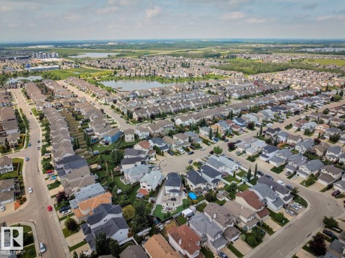 Expansive aerial perspective showcasing a residential neighborhood with numerous single-family homes, mature trees, and multiple streets - 16765 119 Street Nw, Edmonton, AB 
