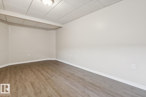 Recessed ceiling with acoustic paneling, neutral wall finishes, wood-finish flooring, and white trim - 16765 119 Street Nw, Edmonton, AB 