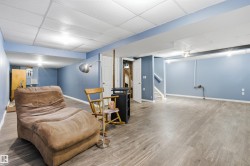 Spacious room featuring wood-finish flooring, drop ceiling, light blue walls, and white trim - 