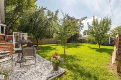 Spacious backyard featuring a multi-level wood deck, a ground-level patio, mature trees, and a wooden fence - 