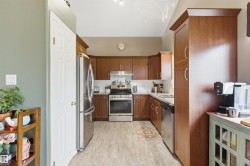 U-shaped kitchen featuring wood-finish cabinetry, stainless steel appliances, and light-toned flooring - 