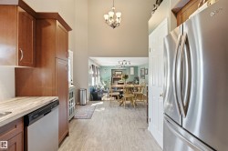 Kitchen featuring stainless steel appliances, wood-finish cabinetry, a light-toned countertop, and a tile backsplash - 