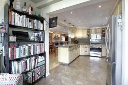 The kitchen features light-colored cabinetry, stainless steel appliances including a refrigerator and oven, a countertop with a stone-like appearance, and tiled flooring - 