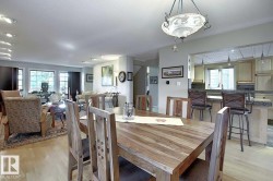 The dining area features a wooden table and chairs, illuminated by an ornate ceiling light fixture - 