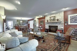 The living space features a stone-clad fireplace and a patterned area rug over hardwood flooring - 