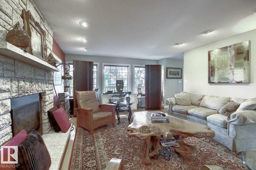 The living area features a stone fireplace with a mantel, recessed lighting, and windows providing natural light - 11126 52 Street Nw, Edmonton, AB - Indoor Photo Showing Living Room With Fireplace
