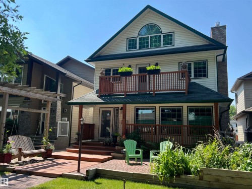 Front exterior featuring a second-story balcony with wood railing, a ground-level deck with steps, a pergola, a brick patio. - 11126 52 Street Nw, Edmonton, AB - Outdoor With Deck Patio Veranda
