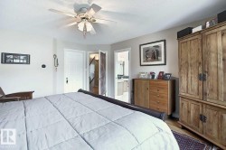 This bedroom features a ceiling fan, hardwood flooring, and a wardrobe with a natural wood finish - 