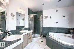 Bathroom featuring a double vanity with two sinks, a glass-enclosed shower, and a built-in jetted bathtub - 