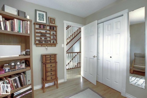 This area features light wood flooring, white trim, and a white closet with bi-fold doors - 11126 52 Street Nw, Edmonton, AB - Indoor Photo Showing Other Room