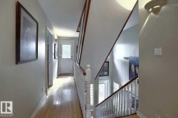 Hallway featuring hardwood floors, light-colored walls, and a white paneled door with a window - 