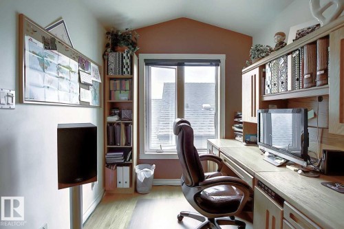Dedicated workspace featuring a window, light wood flooring, and built-in shelving with cabinetry - 11126 52 Street Nw, Edmonton, AB - Indoor Photo Showing Office