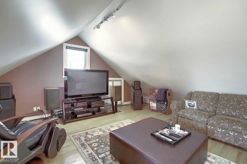 This versatile attic space features sloped ceilings, a window, and track lighting, with light-toned flooring - 11126 52 Street Nw, Edmonton, AB - Indoor Photo Showing Living Room