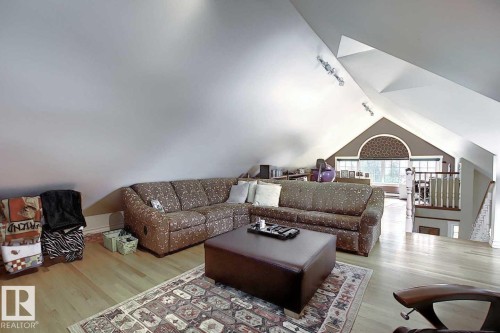 Spacious room featuring sloped ceilings, hardwood flooring, and an arched window - 11126 52 Street Nw, Edmonton, AB - Indoor Photo Showing Living Room