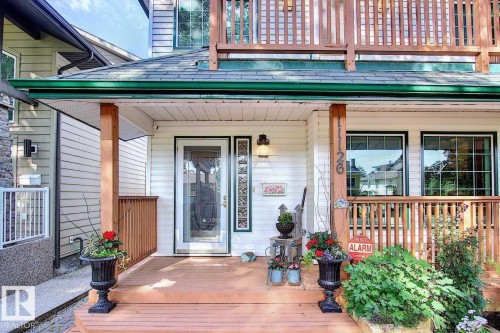 The property features a front porch with wood flooring and railings, a white exterior, and a glass-paneled front door - 11126 52 Street Nw, Edmonton, AB - Outdoor With Deck Patio Veranda With Exterior
