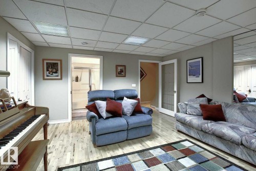 This expansive room features light-toned hardwood flooring, light gray walls, and a drop ceiling with recessed lighting - 11126 52 Street Nw, Edmonton, AB - Indoor Photo Showing Living Room
