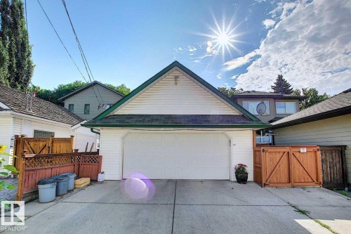 The property features a two-car garage with a white door and an asphalt shingle roof with green trim - 11126 52 Street Nw, Edmonton, AB - Outdoor With Exterior