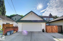 The property features a two-car garage with a white door and an asphalt shingle roof with green trim - 