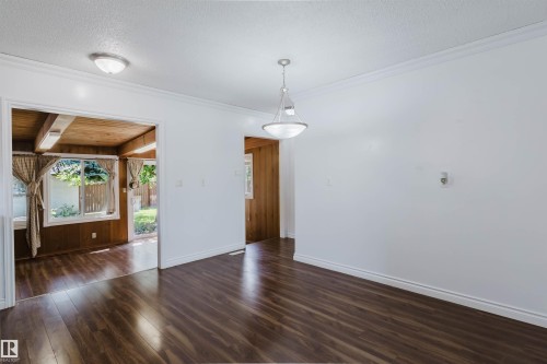 Spacious room featuring wood-finish flooring, white walls, and a contemporary pendant light fixture - 11115 39A Avenue Nw, Edmonton, AB - Indoor Photo Showing Other Room