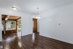 Spacious room featuring wood-finish flooring, white walls, and a contemporary pendant light fixture - 