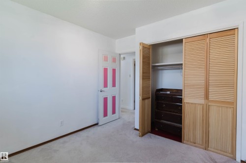 Room featuring light-toned carpeting, white walls, and a door with pink panel accents - 11115 39A Avenue Nw, Edmonton, AB - Indoor