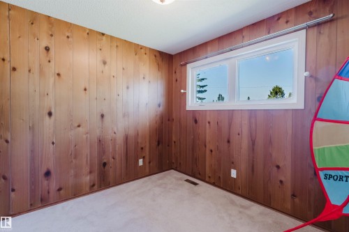 Interior room featuring wood paneling on multiple walls, a white framed window, and carpet flooring - 11115 39A Avenue Nw, Edmonton, AB - Indoor Photo Showing Other Room