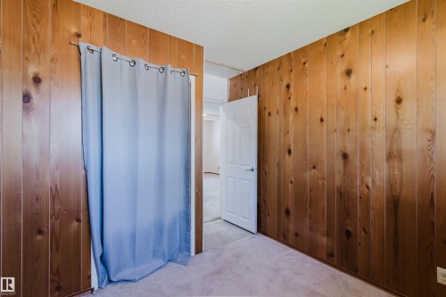 Interior room featuring wood paneling walls and soft carpet flooring - 11115 39A Avenue Nw, Edmonton, AB - Indoor