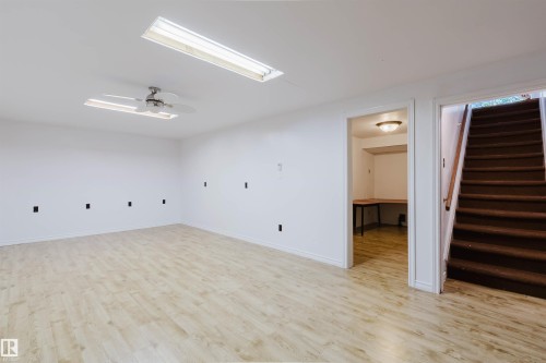 Spacious room featuring light wood-finish flooring, white walls, and a ceiling fan with integrated lighting - 11115 39A Avenue Nw, Edmonton, AB - Indoor Photo Showing Other Room