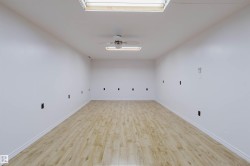Spacious room featuring light wood-finish flooring, white walls, and white baseboards - 