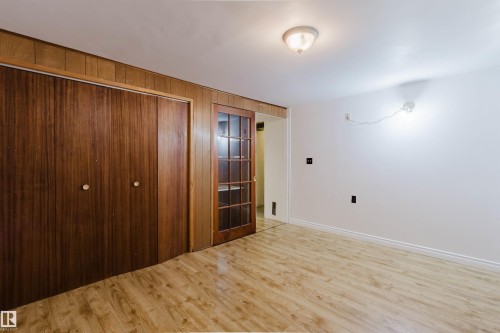 Room featuring wood-finish flooring, white painted walls, and wood paneling accents - 11115 39A Avenue Nw, Edmonton, AB - Indoor Photo Showing Other Room