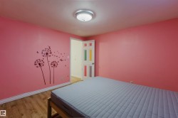Room featuring wood-finish flooring, a flush-mount ceiling light fixture, and a white interior door with decorative color panels - 