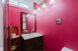 Bathroom featuring a vanity with a white sink, a wood-framed mirror, and a five-bulb light fixture - 