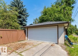 Detached garage featuring a white panel door, concrete driveway, and asphalt shingle roof - 