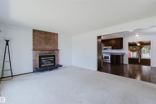 Living area featuring a brick fireplace with a black hearth and mantel - 11115 39A Avenue Nw, Edmonton, AB - Indoor Photo Showing Living Room With Fireplace
