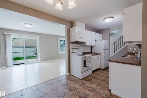 Kitchen with white cabinetry, a double basin sink, and a white appliance package - 134 Callingwood Place Nw, Edmonton, AB - Indoor Photo Showing Kitchen