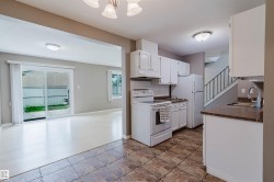 Kitchen with white cabinetry, a double basin sink, and a white appliance package - 
