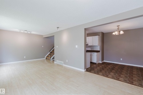 Spacious living area featuring light wood-finish flooring, neutral wall tones, and track lighting - 134 Callingwood Place Nw, Edmonton, AB - Indoor