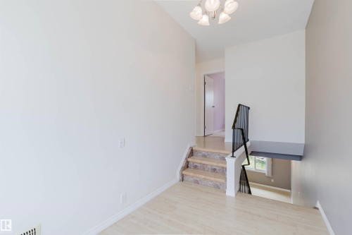 Split-level entry with wood-finish flooring, stone-tread stairs, and a black wrought iron railing - 134 Callingwood Place Nw, Edmonton, AB - Indoor Photo Showing Other Room