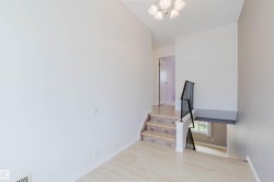 Split-level entry with wood-finish flooring, stone-tread stairs, and a black wrought iron railing - 