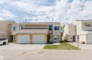 Stucco exterior featuring a two-car garage with white doors, a concrete driveway, and a front entry door with a storm door - 134 Callingwood Place Nw, Edmonton, AB  - Outdoor With Facade 