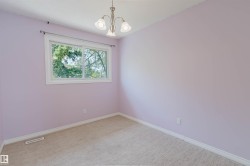 Room with light purple walls, a large window, and beige carpet flooring - 